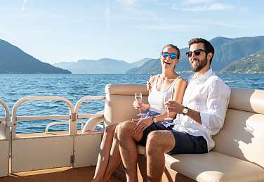 Ein Paar geniesst eine Bootsfahrt mit Champagner auf dem Lago Maggiore bei Sonnenschein