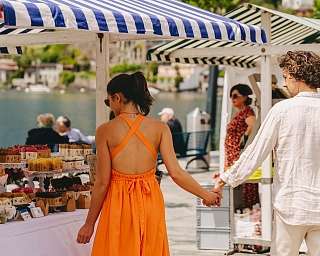 Un couple est assis à une table décorée pour les fêtes sur une terrasse. En arrière-plan, le lac et les montagnes s&#039;étendent sous un ciel du soir.