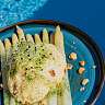 Asperges blanches avec pousses, huile aux herbes et noix grillées, servies sur une assiette bleue
