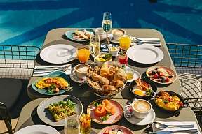 A table right by the pool is richly laid with omelettes, rolls, salmon, fruit and various drinks, including juices and coffee