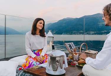 Couple savourant un pique-nique romantique sur la terrasse privée avec vue sur le lac Majeur