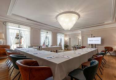 Elegant eingerichteter Veranstaltungsraum im Sunstar Hotel Brissago mit U-förmiger Bestuhlung, weissem Tischtuch, bunten Sesseln und Kristallleuchter