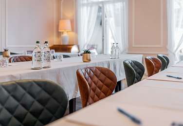 Primo piano delle eleganti poltrone in pelle e tessuto del Salone Rosa presso il Sunstar Hotel Brissago con tovaglia bianca e decorazione tavola curata