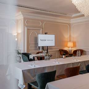 Luminosa sala eventi presso il Sunstar Hotel Brissago con sedute eleganti, schermo per presentazioni e lampadario di cristallo – ideale per meeting e celebrazioni private