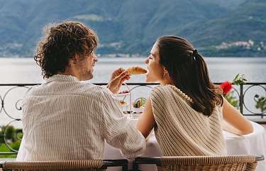 Couple profitant d'un moment tranquille sur la terrasse du Sunstar Hotel Brissago avec vue sur le Lac Majeur et le cadre montagneux.